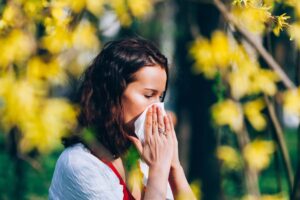 Cute girl in the park, sneezing, having spring allergies