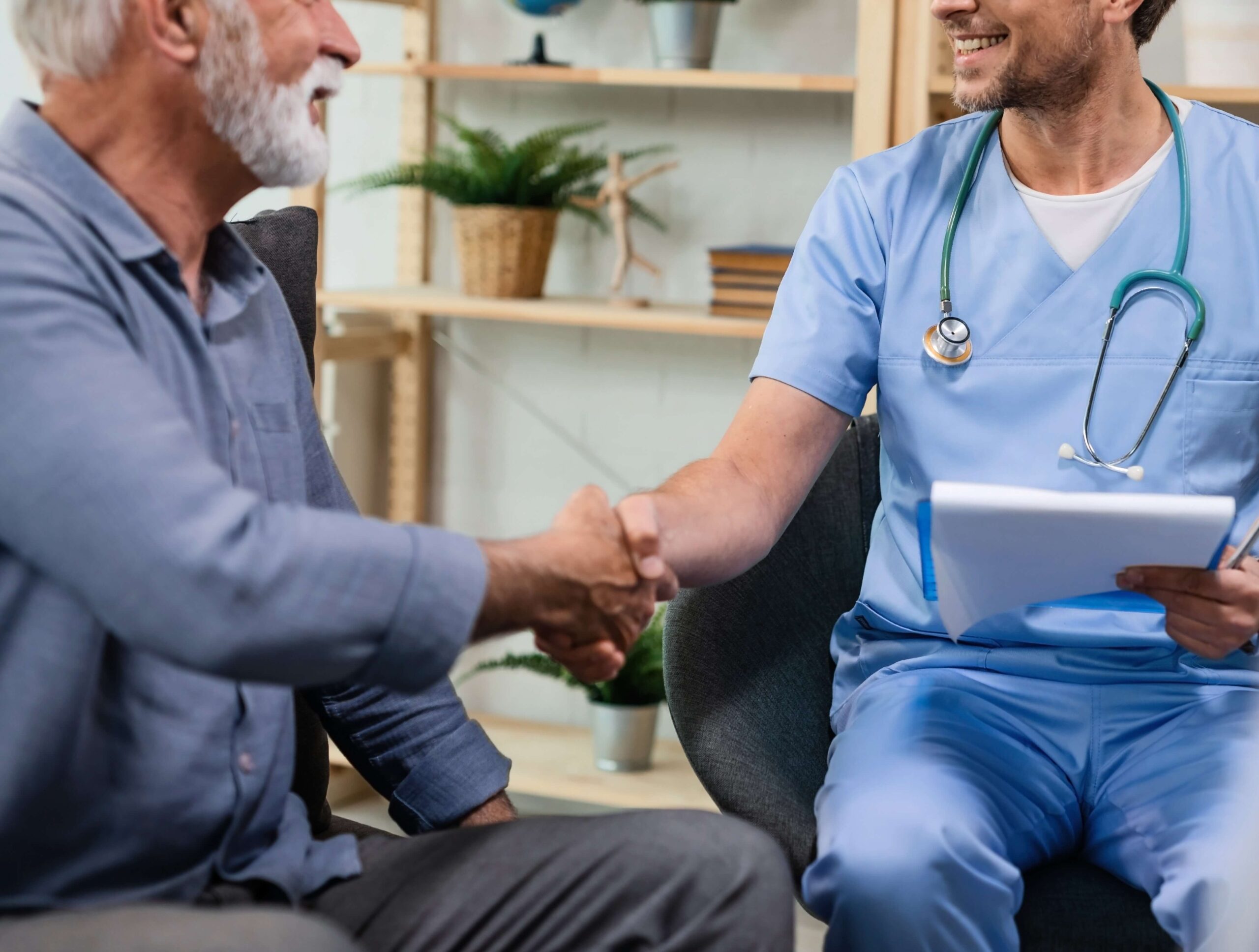 Headaches and Chronic Migraines, image of a male doctor, on the right side of the image, shaking hands with an older male patient, on the left side of the image.