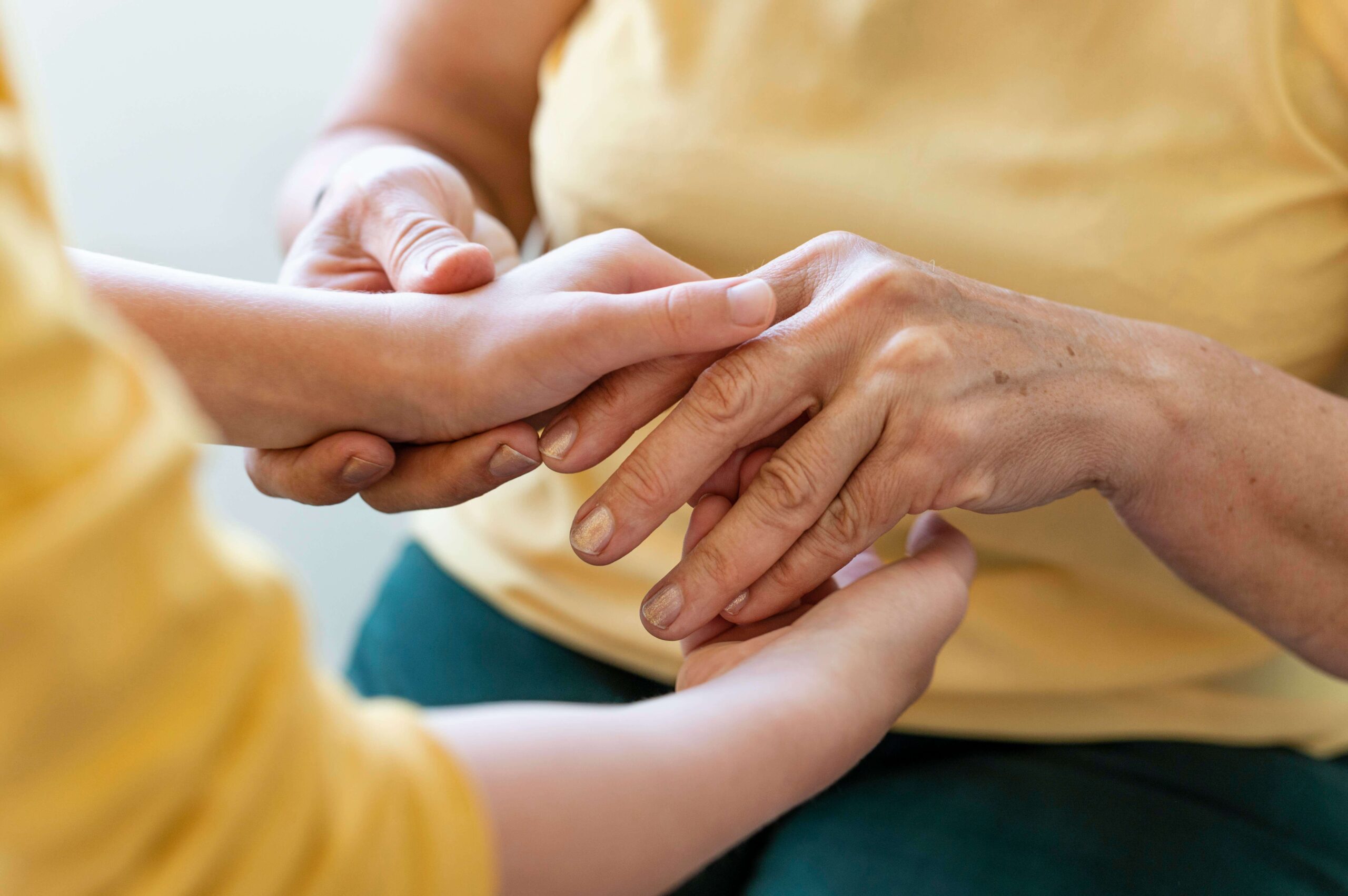Multiple sclerosis, image of a woman with stiff fingers holding the hands of a young person.