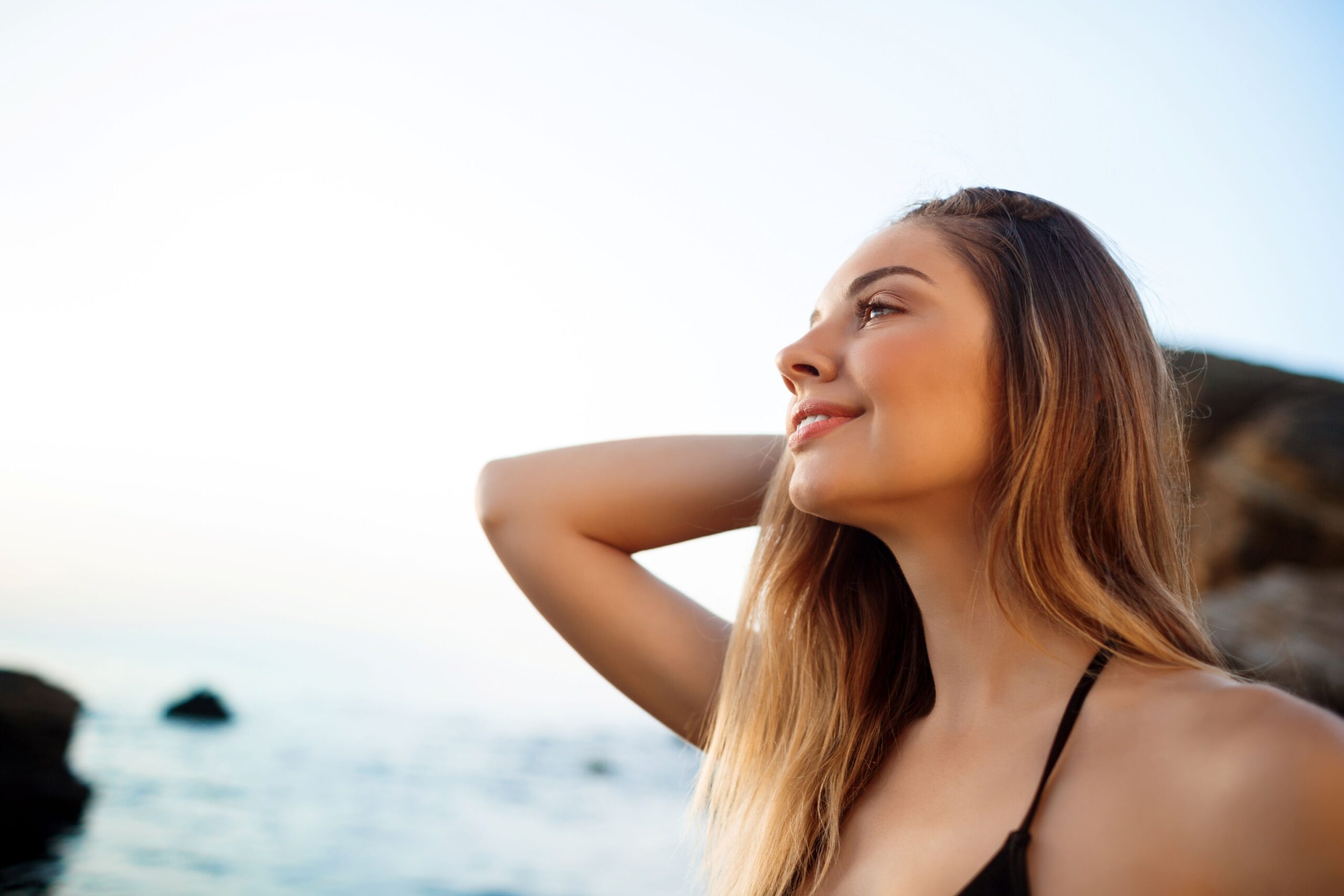 PDRN Therapy, image of a woman with long blonde hair looking out into the distance with her right arm extended behind her head.