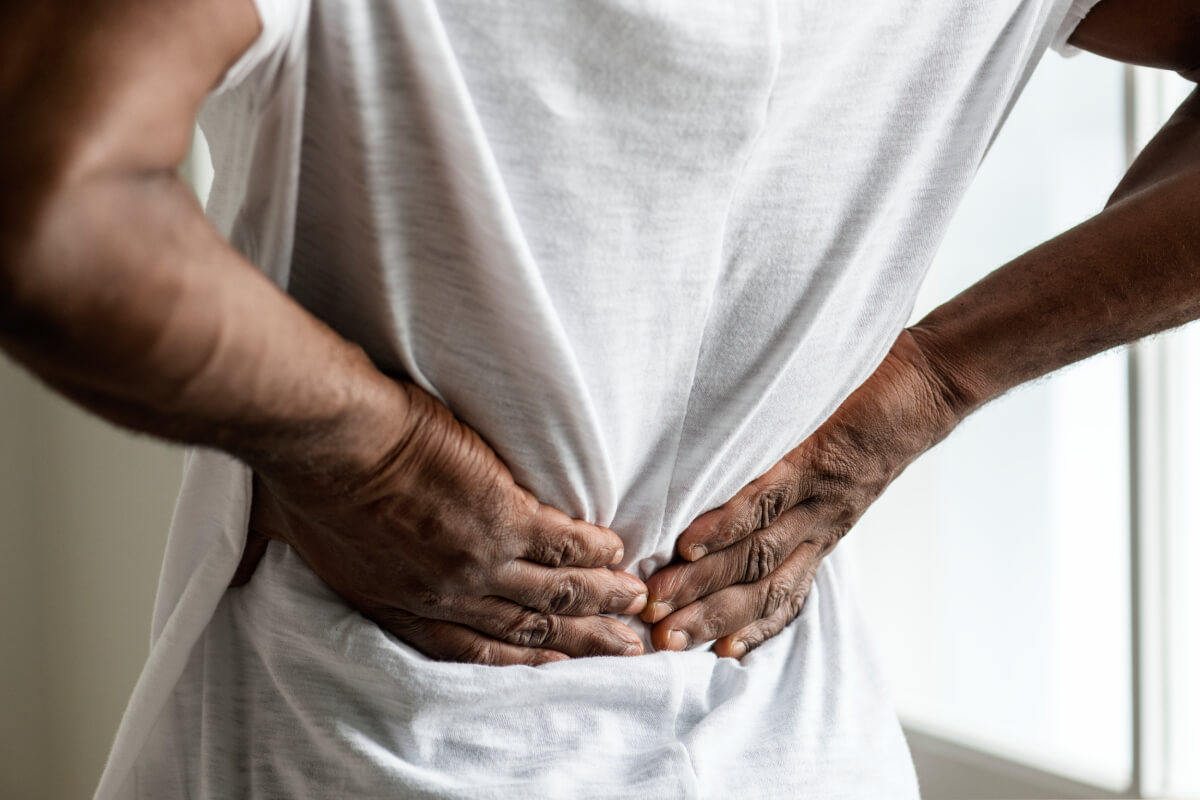 Adrenal Stress, image of a man wearing a white t-shirt with both of hands grasping his lower back.