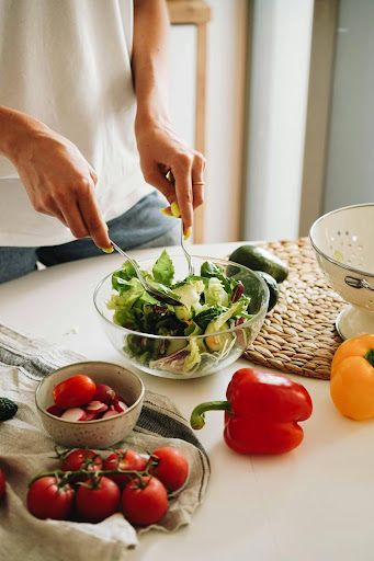 Gastroesophageal Reflux Disease (GERD), image of a woman’s hands holding forks and tossing a salad.